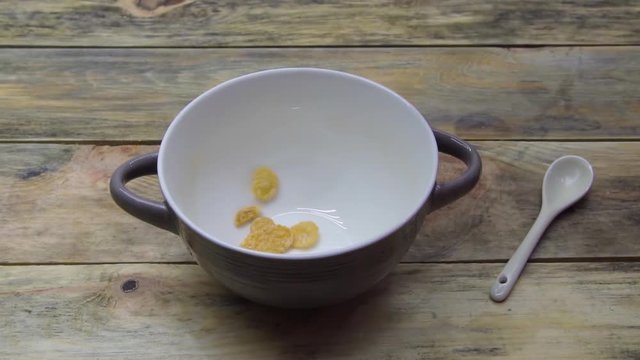 corn flakes fall asleep in a plate on a wooden background. Slow motion.