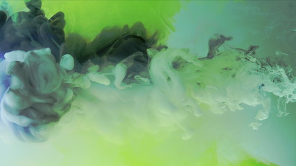 Multicolored composition from ink streams. Black and white streams of ink float and mix in the center of the composition. Colorful abstract combination of acrylic rainbow ink on a light green