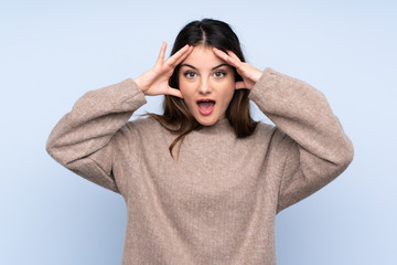 Young brunette woman wearing a sweater over isolated blue background with surprise expression