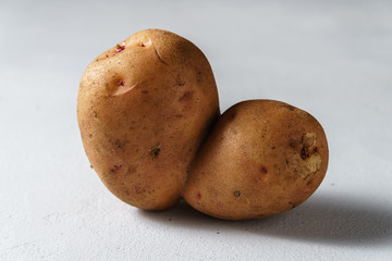 The concept of ugly vegetables and food waste. An ugly potato in the shape of a heart on a light...