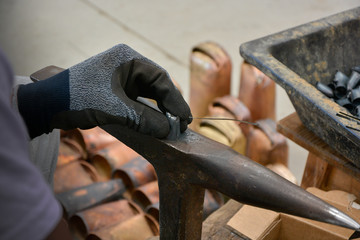Hand with black glove working in cowbell manufacturing workshop