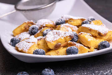 Kaiserschmarrn, traditional austrian cut-up and sugared pancake with fruits on a white plate