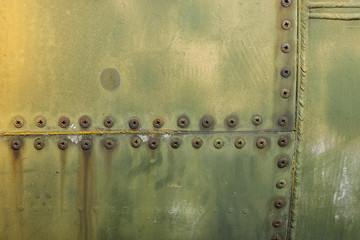 Details of the fuselage of an old aircraft. Old camouflage surface with exfoliated paint and rivets on a military aircraft.