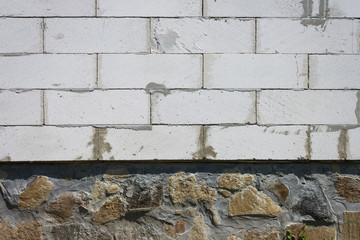 The texture of the stone foundation of the house along with the wall. Close-up