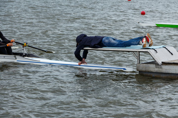 Stakeboat volunteer on starting platform holding a sport rowing boat.