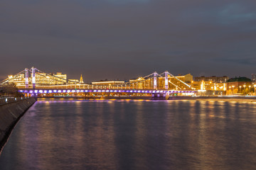Fototapeta na wymiar Glowing bridge over the river. The far plan. Moscow night