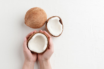 two half of coconut on white background. woman holding coconut with two hands.