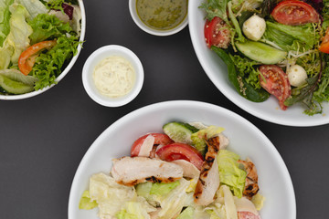 white deep plates with fresh salad ingredients mixed with sauce placed on an attractive background. A place for a menu, banner or advertisement