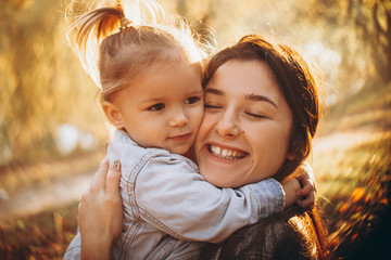 The daughter embracing her mother in the park spending a weekend on a walk in autumn park....