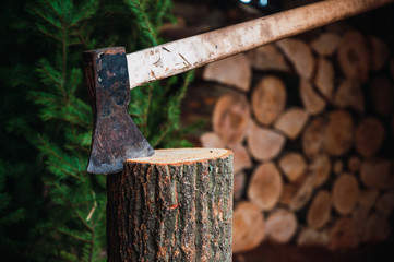 Ax on a wooden throne ready to cut firewood, background cut firewood and pine tree