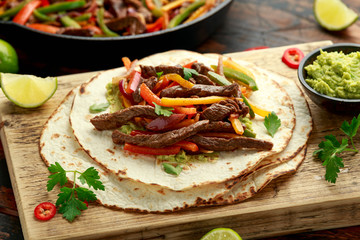 Beef Steak Fajitas with tortilla mix pepper, onion and avocado on wooden board
