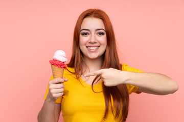 Young girl with a cornet ice cream over isolated background and pointing it