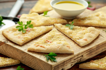 Fresh slices of Garlic pizza on wooden board with herbs.