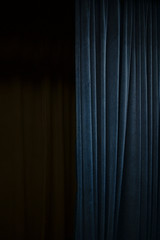 Dark blue velvet curtain on one side of a black theatre stage, vertical event background with large...