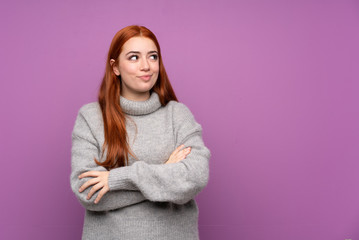 Fototapeta premium Redhead teenager girl over isolated purple background standing and looking to the side