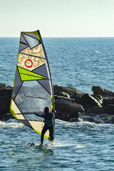 windsurfing, windsurfer young man on a windsurf on sea water.