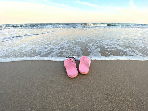 Summer holiday concept. Pair of pink sandals on the beach.