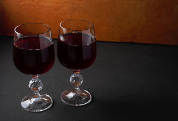 two wine glasses with grapevine on a dark table
