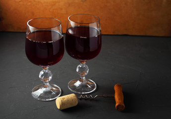 two wine glasses with grapevine on a dark table