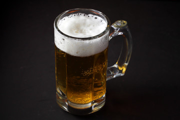a glass of beer stands on a dark table
