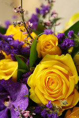 Close-up of a beautiful spring bouquet with yellow roses and purple orchids. Decorative composition of a greeting card for a birthday holiday. Copy space.