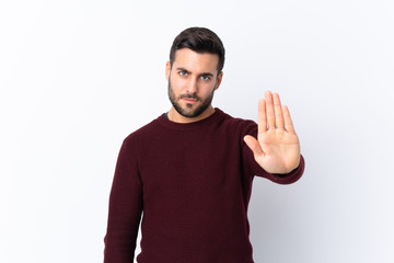 Fototapeta premium Young handsome man with beard over isolated white background making stop gesture