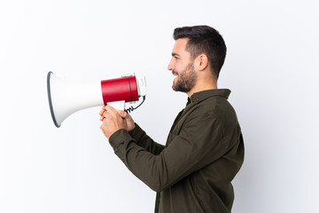 Young handsome man with beard over isolated white background shouting through a megaphone