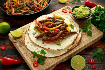 Beef Steak Fajitas with tortilla mix pepper, onion and avocado on wooden board
