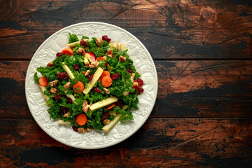 Kale salad with dried cranberry, carrots, walnuts and apple. healthy vegan food.