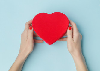 Obraz premium Woman holding red heart shaped box on the blue background. Valentine's day, mother's day, birthday, holiday concept.