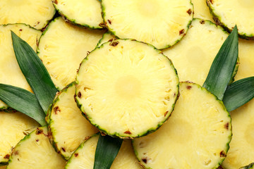 Fresh juicy pineapple slices with green leaves, tropical fruits background