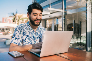 Young man using his laptop in a coffee shop.