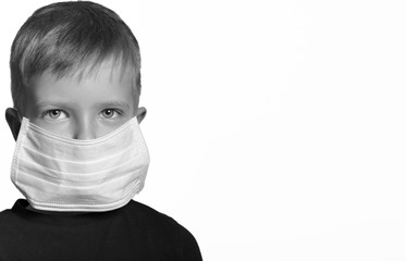 face of a mask-wearing child with fear in the eye. On a white background . Copyspace. black and white photography