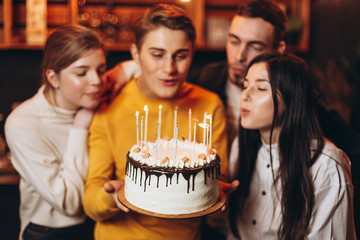 young handsome man holding a cake which he gave his friends for his birthday. Birthday celebration with best friends