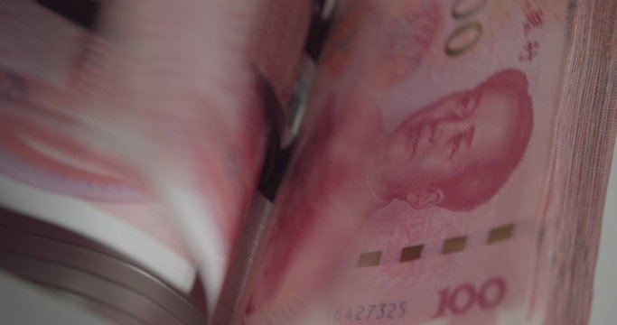 Closeup of electronic or automatic machine for counting bills or money. Banknote or currency counter counts one hundred / 100 CNY Chinese yuan cash, banking and commercial activity, financial concept.