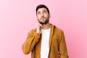 Young handsome man with beard wearing a corduroy jacket over pink background thinking an idea