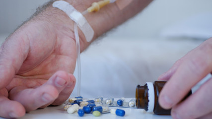Suffering Man with a Perfusion in Hand and Take Medical Pills from the Table, Nursing in Emergency...