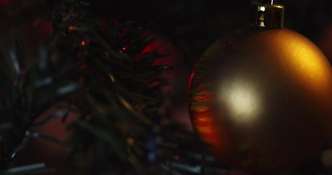 gold Christmas ornament hanging on a tree with flickering lights