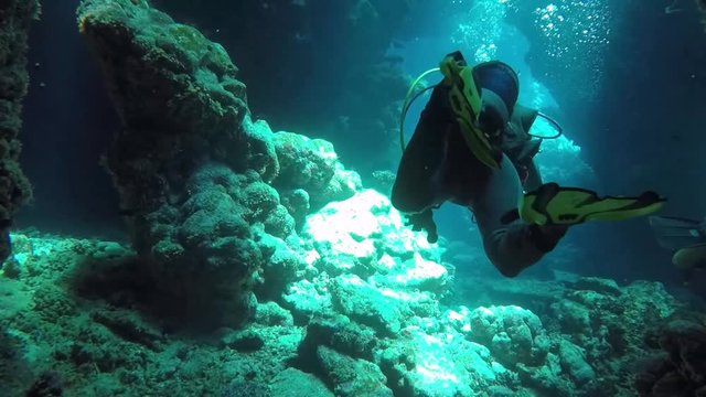 Female Scuba Diver swimming through a cave in the blue waters of the Red Sea Egypt