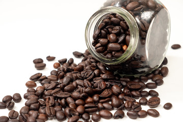 Fototapeta premium Scattered coffee beans from a transparent jar on a white background