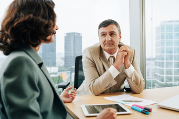 Middle-aged Caucasian man and unrecognizable woman working together in modern office, horizontal shot