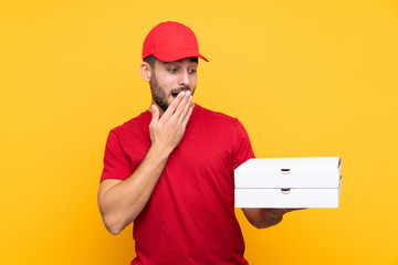 pizza delivery man with work uniform picking up pizza boxes over isolated yellow background with...