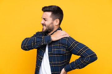 Fototapeta premium Young handsome man with beard over isolated yellow background suffering from pain in shoulder for having made an effort