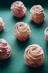 pink muffins with cream on a dark green background