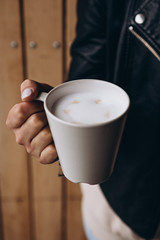 a cup of fragrant morning coffee before work or school. Photo of the female hands  holding a cup with pictures of little hearts. Ideal for advertising or banner