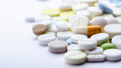 bright pills of different shapes and colors close-up on a white background, soft focus