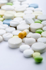 multicolored pills of different shapes on a white background close-up, soft focus, vertically