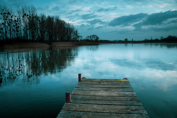 Cloudy and cold winter evening, freezing lake with a pier