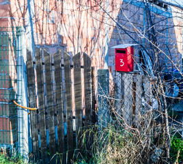 Novi Sad, Serbia - February 01. 2020: Red metal mailbox on an old wooden fence 