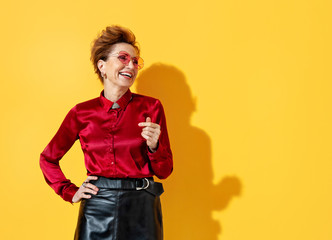 Happy smiling woman looking away. Photo of elderly woman in love in red shirt on yellow background